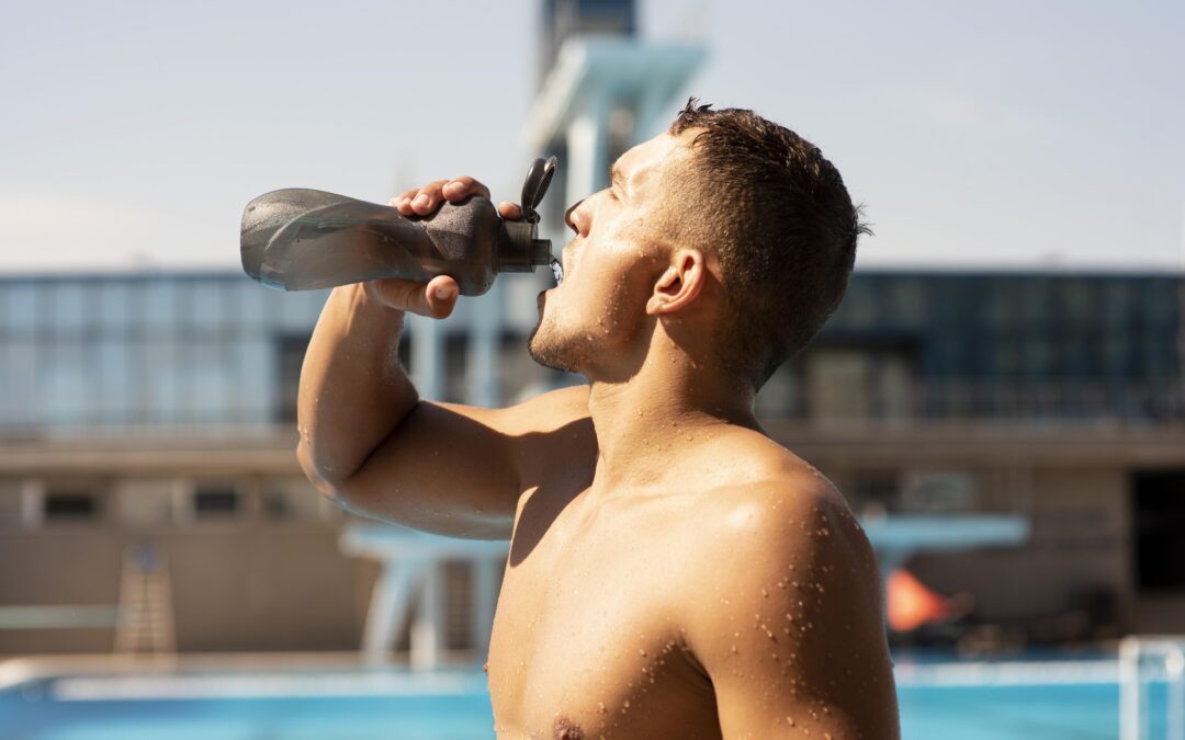 Nageur buvant de l’eau pour maintenir une bonne hydratation après l’entraînement.